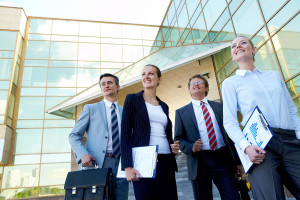 Group of confident employees with documents looking aside outdoors